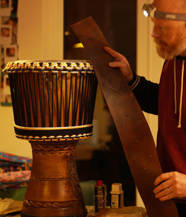 Professional djembe repair workshop with Al working on drum restoration and specialized repair tools