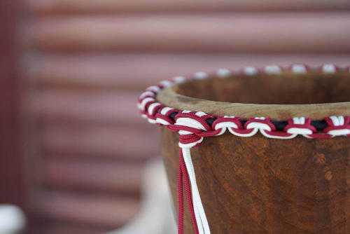 A double crown in red and white rope resting on a drum shell before being assembled with the skin